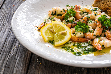 Fried prawns with garlic and parsley in oil olive on wooden table 