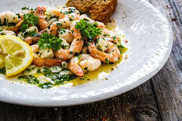 Fried prawns with garlic and parsley in oil olive on wooden table 