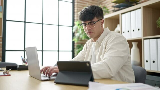 Young hispanic man business worker using laptop and touchpad working at office