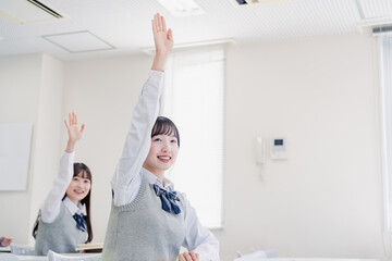 手を上げて発表をする女子高生