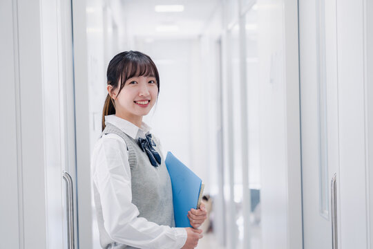 教材を持って校内を歩く女子高生