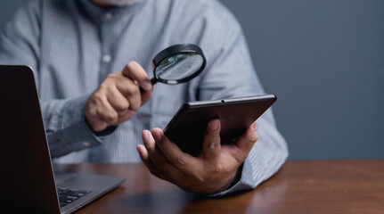 Concept of internet security System. Businessman examines a tablet with a magnifying glass. internet security System warning alert security, Businessman developer using technology with caution warning