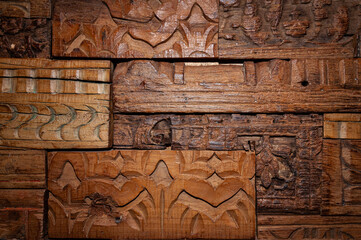 Antique wood tile laid out on the wall, with hand carved patterns on the surface.
