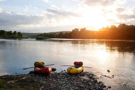 Orange and yellow packrafts rubber boats with padles on a sunrise Dnister river. Packrafting background. Active lifestile concept