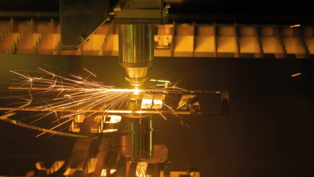 Automatic cnc laser cutting machine working with sheet metal with many orange sparks at plant, factory. Metalworking, industrial, manufacturing, technology and equipment concept