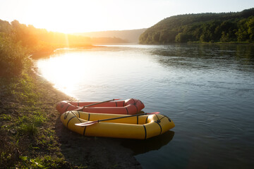 Orange and yellow packrafts rubber boats with padles on a sunrise river. Packrafting. Active lifestile concept