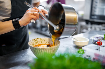 woman chef cooking Tom Yam soup on restaurant kitchen