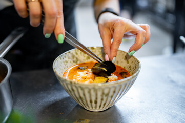 woman chef cooking Tom Yam soup on restaurant kitchen