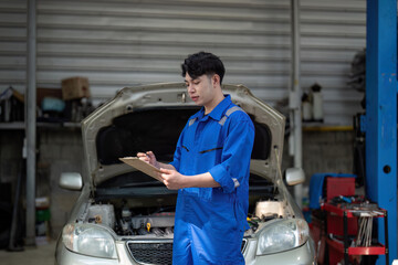 Vehicle service maintenance asian man checking under car condition in garage. Automotive mechanic maintenance checklist document. Car repair service concept