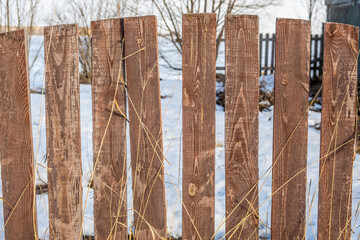 A fence made of wooden boards in winter on the street.