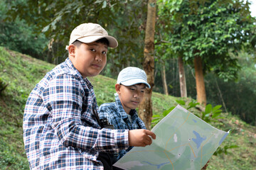 Asian boys using binoculars to do the birdwatching in tropical forest during summer camp, idea for learning creatures, wildlife animals and insects outside the classroom.