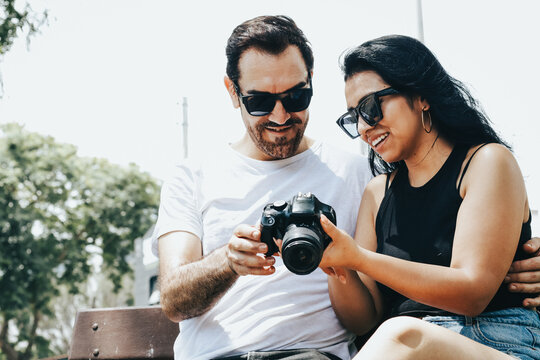 Photograph of a couple looking at photos on a reflex camera. Lifestyle concept and people.