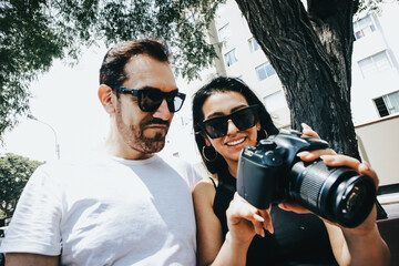 Photograph of a couple looking at photos on a reflex camera. Lifestyle concept and people.