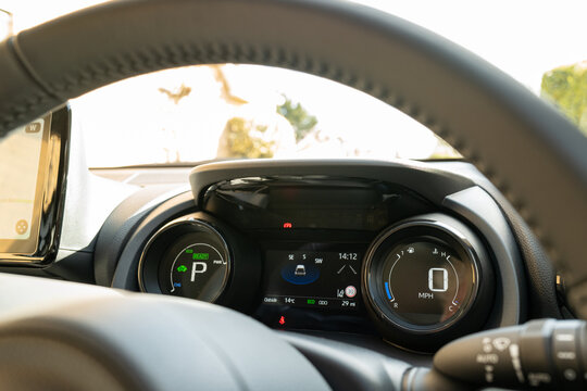 Cockpit view of a new, Japanese hybrid hatchback car. Showing the dual LCD dashboard and part of the large LCD navigation display on the left.
