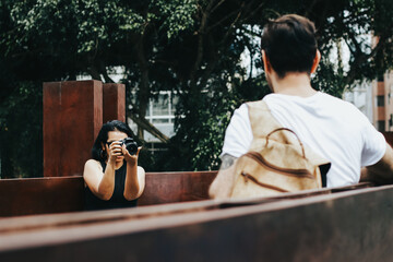 Photograph of woman taking pictures with a camera to a man. Vacation, tourism, and lifestyle concept.