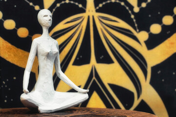 A white wooden statue of a woman sat cross-legged against a karmic, cosmic space background -...