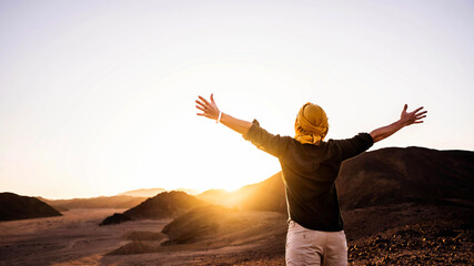 Happy man with arms outstretched standing on the top of the mountain enjoying sunset - Successful...