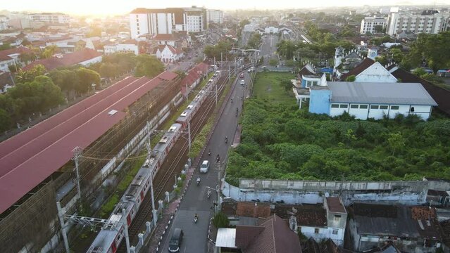Aerial view of passenger train crossing rail bridge in near Tugu Station.