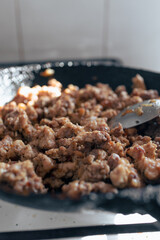Fried meat in a pan. The process of frying minced meat in an old frying pan