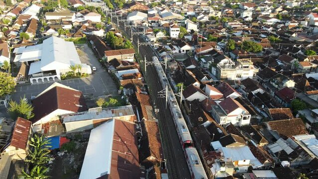 Aerial view of passenger train crossing rail bridge in near Tugu Station.