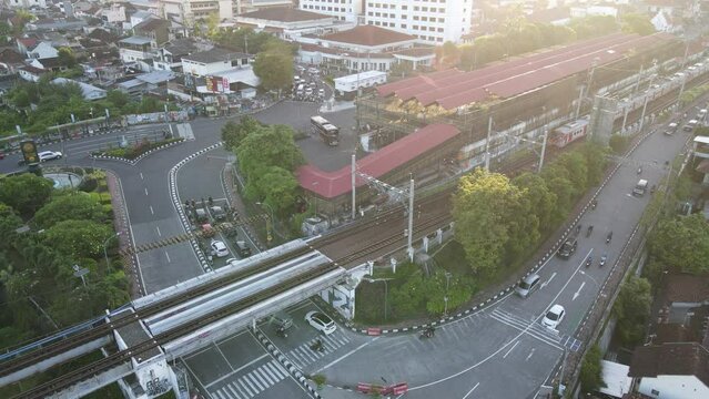 Aerial view of passenger train crossing rail bridge in near Tugu Station.