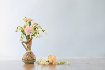 flowers in vintage jug on wooden table on white  background