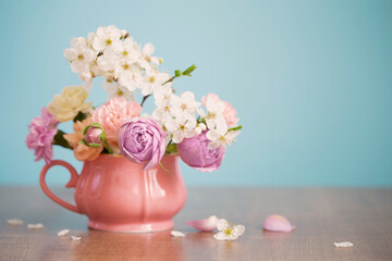 beautiful spring flowers in vintage cup in pastel colors on blue background