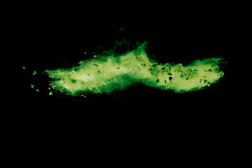 Split debris of  stone exploding with green powder against black background.