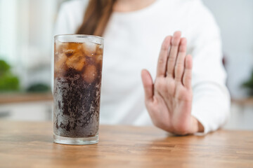 Limits sugar diet in food concepts. Young woman showing bad hand symbol to soft drink soda that...
