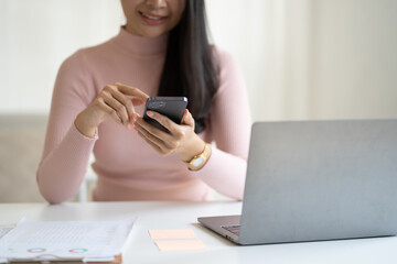 Fototapeta premium Close up view of young female using smartphone while sitting in a comfortable room.