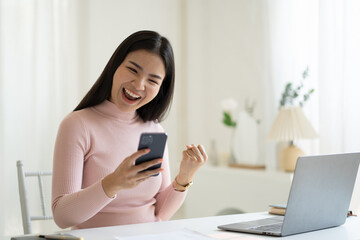 Young pretty Asian woman impressed with a good news, raised fists scream yes, celebrating success on her own.