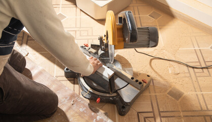 Worker cutting part of furniture with cutting machine.