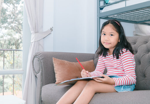 cute girl paint or do homework on sofa in living room, learn and relax