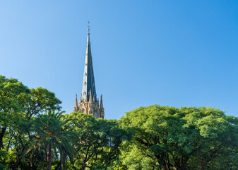 Leafy view of the tall church spire and clock tower of San Isidro cathedral near Buenos Aires in Argentina