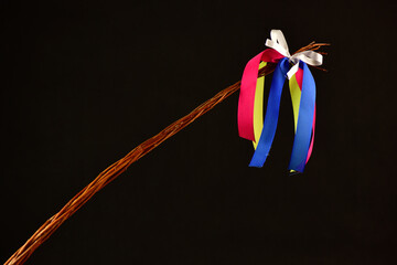 Traditional Czech Easter whip with colored ribbons 
from willow branches on the black background 