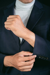 Midsection of businessman gesturing adjusting suit sleeves on black background