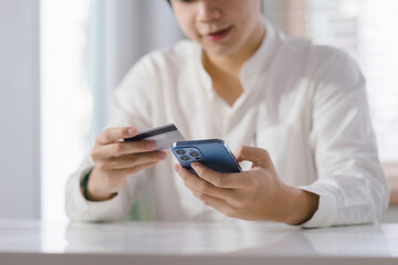 Cropped shot of millennial man is paying with a credit card online while placing orders via mobile internet and making transactions using a mobile banking application.