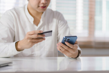 Cropped shot of millennial man is paying with a credit card online while placing orders via mobile internet and making transactions using a mobile banking application.