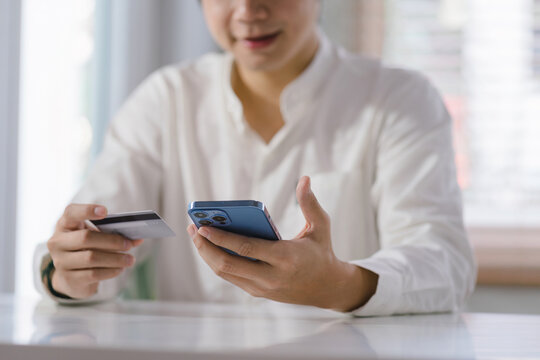 Cropped shot of millennial man is paying with a credit card online while placing orders via mobile internet and making transactions using a mobile banking application.