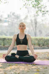 A beautiful sportswoman in sportswear is Practicing Breathing Exercise in Autumn city park background.