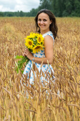 Smiling Young Caucasian Woman with Bouquet of Sunflowers Posing in the Wheat Field 