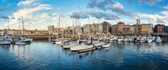 Naklejka premium Panoramic marina with many small sailing boats docked on the shore of the city of Gijon, Asturias, Spain.