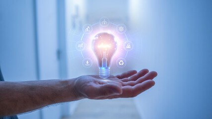 Hologram light bulb above hand with icons and with energy sources concept