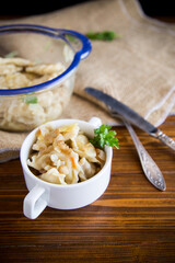 cooked dumplings with potatoes and fried onions on a wooden table.