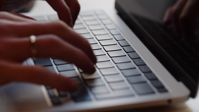 A man with a ring on his ring finger is typing on a computer keyboard. Close-up of male hands typing on a laptop keyboard.