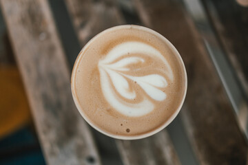 Cup of coffee to go on the wooden table with latte art. Street coffee, top view. High quality photo