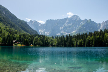 Fototapeta na wymiar View of Lago Inferiore die Fusine in the Julian Alps of northeastern Italy with the dramatic rock face of Mount Mangart in the background