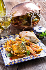 Traditional Portuguese seafood cataplana with king prawns, mussels and fish in wine sauce served as close-up in a design cataplana pot