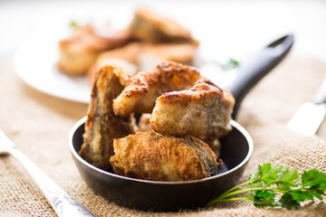 A piece of hake fish fried in a crispy crust, in a plate.