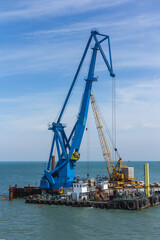 Fototapeta na wymiar Construction work at the port dock crane in the bay of the sea